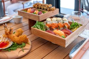 two baskets of food on a wooden table with sushi at Petram Resort & Residences in Savudrija