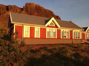 una casa rossa e bianca di fronte a una montagna di Kría Cottages a Skeljabrekka