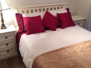 1 dormitorio con cama blanca y almohadas rojas en The Old Dispensary, en Kinsale