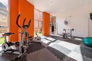 un gimnasio con máquinas de ejercicio y paredes de color naranja en Viaggiato Guemes en Córdoba