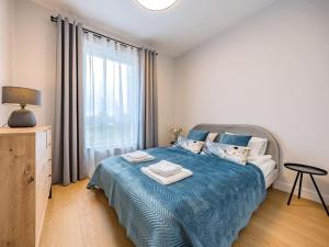 a bedroom with a bed with a blue blanket and a window at Hello Apartments RIO with private parking in Gdańsk
