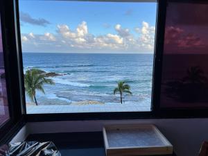 una ventana con vistas al océano con palmeras en Maravilhoso 3 quartos vista mar Ondina Apart, en Salvador