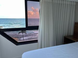 a bedroom with a bed and a view of the ocean at Maravilhoso 3 quartos vista mar Ondina Apart in Salvador