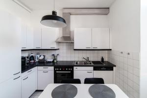 a white kitchen with white cabinets and a table at Giuka Apartment by Quokka 360 - close to the station in Massagno