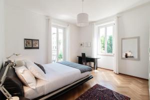 a white bedroom with a bed and a desk at Giuka Apartment by Quokka 360 - close to the station in Massagno