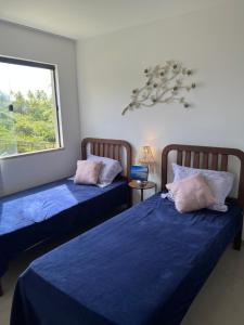 a bedroom with two beds with blue sheets and a window at apto vista mar imbassai in Imbassai +21 photos