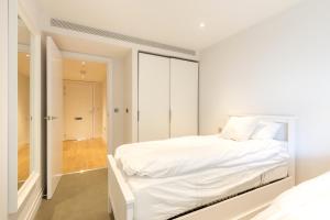 - une chambre blanche avec un lit blanc et un placard dans l'établissement Stylish 2 Bed Flats Near US Embassy, à Londres