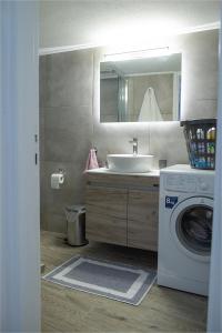 a bathroom with a sink and a washing machine at Sea Front Sophia Porto Rafti in Porto Rafti