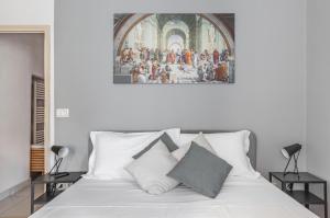 a bedroom with a white bed with a painting on the wall at Giardino della Fortezza & San Lorenzo Central Flat in Florence