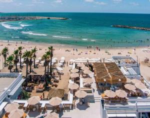 Prime Location 2BR Beach Flat في تل أبيب: شاطئ فيه مظلات وناس على الشاطئ