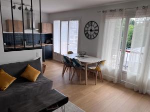 sala de estar con mesa y reloj en la pared en Centre, Soulages, Amphithéâtre - clim balcon parking, en Rodez