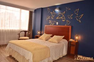 um quarto com uma cama e uma parede azul com decalques de pássaros em Hotel Litavira Vintage em Sogamoso
