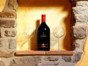 a bottle of wine and two wine glasses on a wall at B&B Il Fortino in Talla