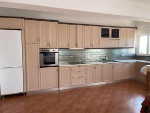 a kitchen with wooden cabinets and white appliances at Anastasias apartments in Sarandë