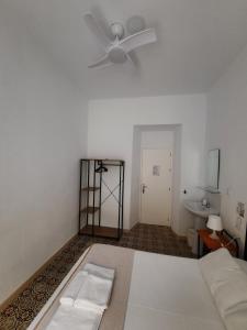 1 dormitorio con cama blanca y ventilador de techo en Pensión Las Cuatro Naciones, en Cádiz