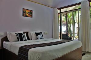 a bedroom with a large bed and a balcony at Sai Valentines in Canacona