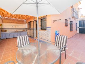 einen Glastisch mit zwei Stühlen und einem Sonnenschirm in der Unterkunft Cubo's Casa Ronda del Olivar in Pizarra