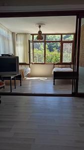 een woonkamer met een tv en een bed en ramen bij Ayten's Sweet House in Trabzon