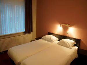 a bedroom with a large white bed with two pillows at Hotel Du Soleil in Knokke-Heist