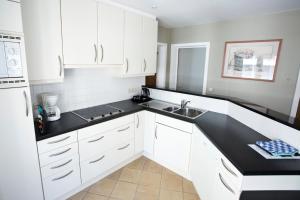 a kitchen with white cabinets and a black counter top at Hotel Du Soleil in Knokke-Heist