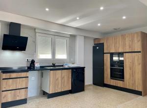 a kitchen with wooden cabinets and a black refrigerator at UIM Mediterraneo Emilio Llopis Wifi in Sagunto