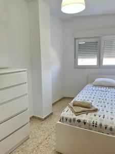 a white bedroom with a bed and a dresser at UIM Mediterraneo Emilio Llopis Wifi in Sagunto