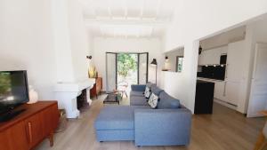 ein Wohnzimmer mit einem blauen Sofa und einem TV in der Unterkunft Villa Everblue Sainte-Maxime - Domaine privé - Piscine in Sainte-Maxime