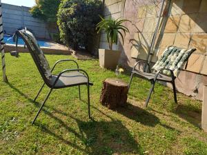dos sillas sentadas en la hierba junto a un tronco de árbol en Charm Nest - Uncapped Wi-fi & Self Check-in, en Ciudad del Cabo