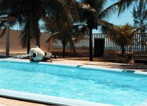 uma piscina com palmeiras e um edifício em Casa LUXO Guaibim em Guaibim