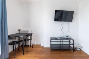 Habitación con mesa y TV en la pared. en Cénoslocs - Paris à vos pieds pour 6 pers., en Noisy-le-Sec