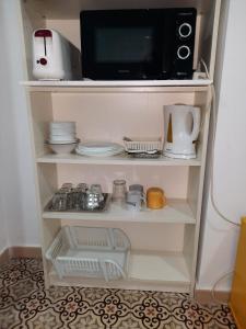 estante con microondas y algunos platos y microondas en Pensión Las Cuatro Naciones, en Cádiz