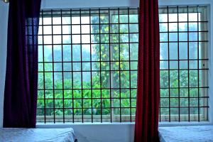 a bedroom with a large window with red curtains at Coffee Crown Homestay - Water Falls, Trek, Home Food, Estate in Sakleshpur