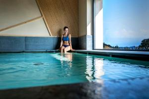 uma mulher de biquíni sentada à beira de uma piscina em Fornella Camping & Wellness family resort em San Felice del Benaco