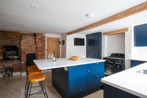 una cucina con armadi blu e piano di lavoro bianco di The Bakery ad Arundel