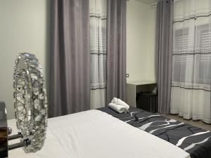Schlafzimmer mit einem Bett mit weißer Bettwäsche und Vorhängen in der Unterkunft B&B Akoya Capo Vaticano in Capo Vaticano