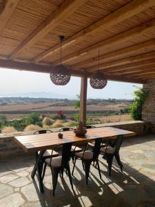 une table et des chaises en bois sous un toit en bois dans l'établissement Marikos House, Pyrgaki Alyko Naxos, à Plage d'Aliko