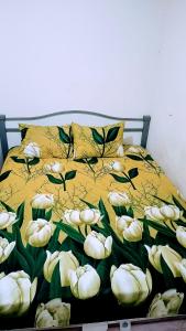 un letto con una coperta gialla con fiori bianchi di Apartemen Cibubur village by ipol a Cisalak