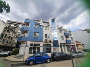 a blue building with two cars parked in front of it at MDM APARTMENT CITY CENTER in Ruse
