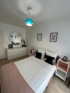 1 dormitorio con 1 cama blanca grande y espejo en Cosy appartement Boulogne en Boulogne-Billancourt