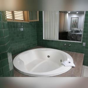 a white bath tub in a green tiled bathroom at Minas Palace Hotel in Passos