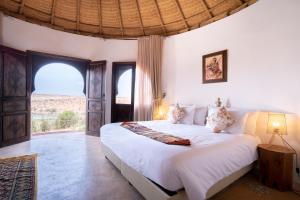 a bedroom with a large bed and a large window at Safa Boulaouane in Douar Annbirat