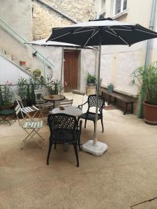 a table and chairs with an umbrella on a patio at Cottage AU TERMINUS 3 climatisé in Hautvillers