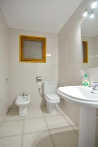 uma casa de banho branca com um lavatório e um WC em Brisas Vista Mar em Sa Ràpita