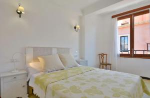 a white bedroom with a bed and a window at Brisas Vista Mar in Sa Ràpita