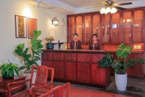 due donne in piedi in un bar in una stanza con piante di Phongsavath Boutique Hotel a Vientiane