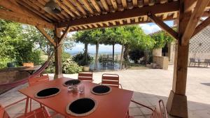 a table and chairs under a wooden pergola at Chambre avec cuisine, vue et piscine privée au cœur du Beaujolais in Blacé