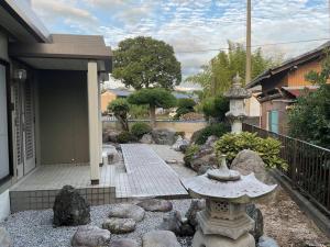 um jardim com uma fonte de pedra em frente a uma casa em 貸別荘せせらぎ em Taga