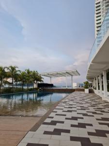 uma piscina com palmeiras e um edifício em Seaview Condo 10pax #10minQueensbay #15minSpice em Bayan Lepas