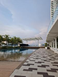 a swimming pool with palm trees and a building at Seaview Condo 10pax #10minQueensbay #15minSpice in Bayan Lepas
