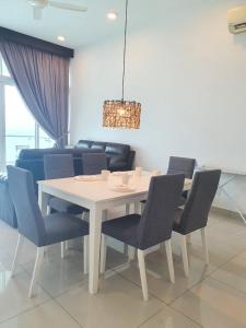 uma sala de jantar com uma mesa branca e cadeiras azuis em Seaview Condo 10pax #10minQueensbay #15minSpice em Bayan Lepas